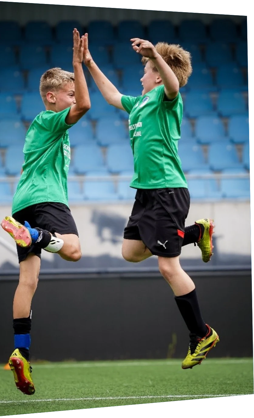 Twee schoolvoetballers geven elkaar een high five tijdens het ASML Schoolvoetbaltoernooi in Eindhoven