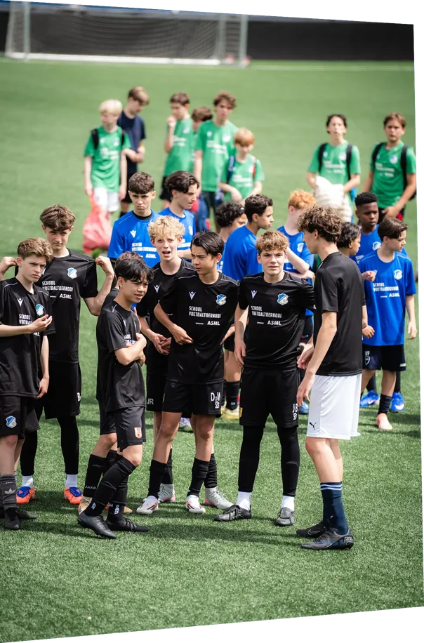 Schoolteams in zwarte, blauwe en groene shirts wachten op het veld tijdens het ASML Schoolvoetbaltoernooi